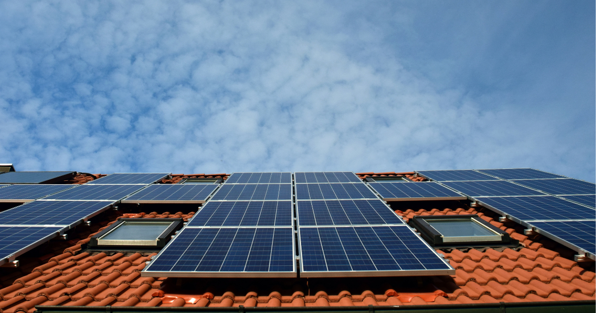  Painéis solares instalados em um telhado de cerâmica laranja sob um céu parcialmente nublado. A imagem destaca a integração da energia solar em residências.